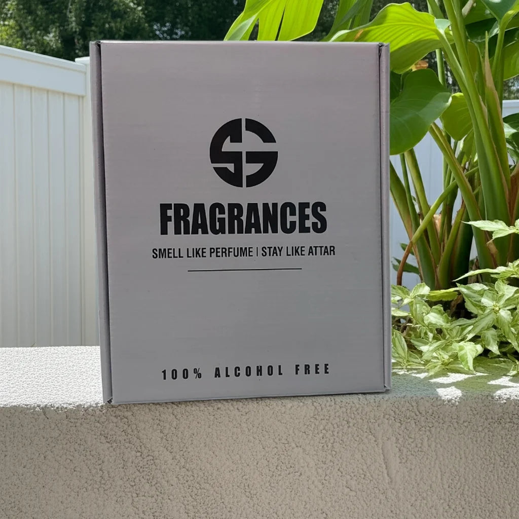 Box labeled 'SG Fragrances' with branding on a concrete surface with plants in the background. Attar combo set