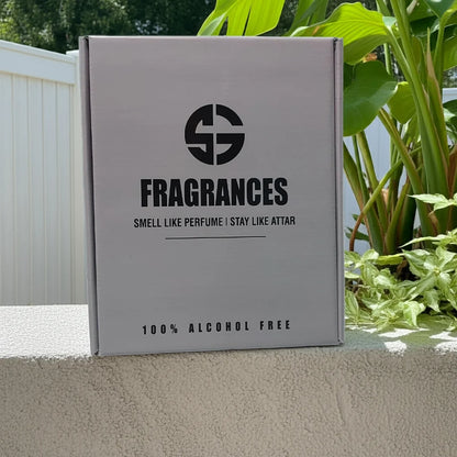 Box labeled 'SG Fragrances' with branding on a concrete surface with plants in the background. Attar combo set
